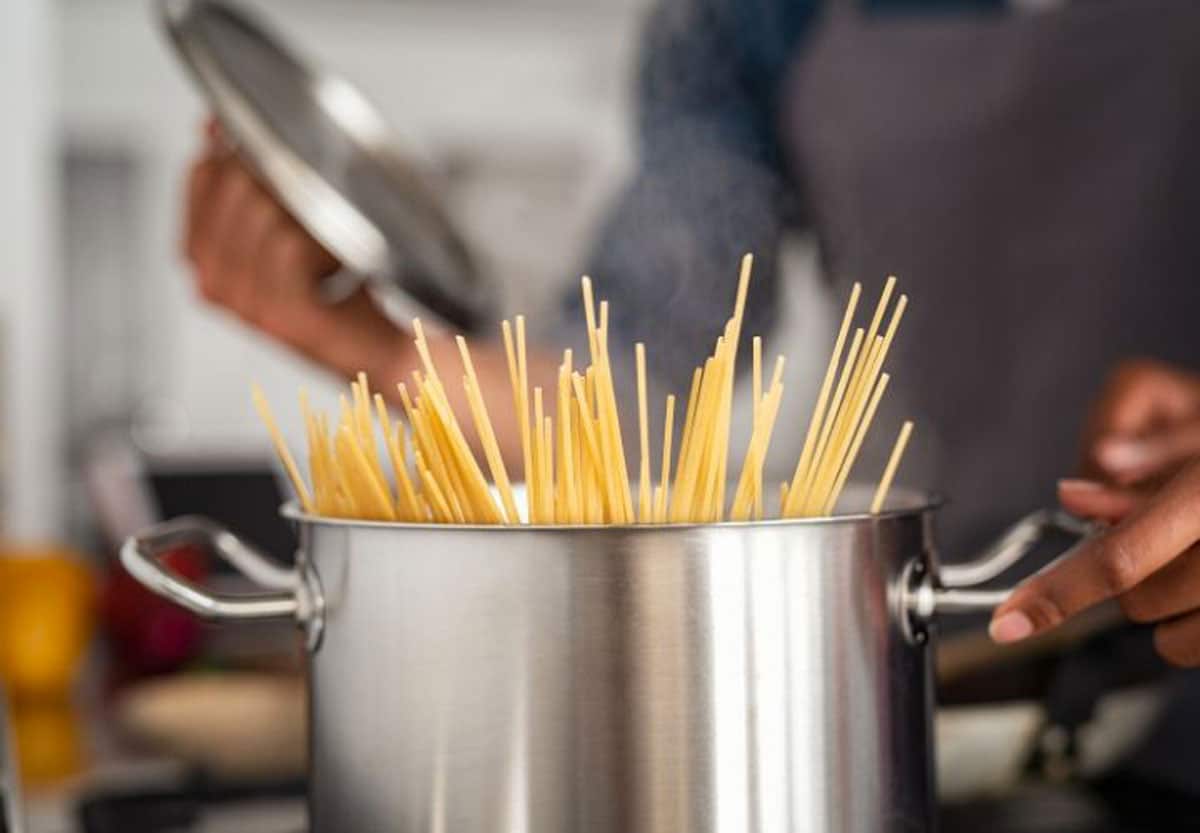 cooking spaghetti in a large silver pot.