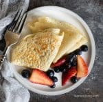 Folded crepes on a plate with fresh berries.