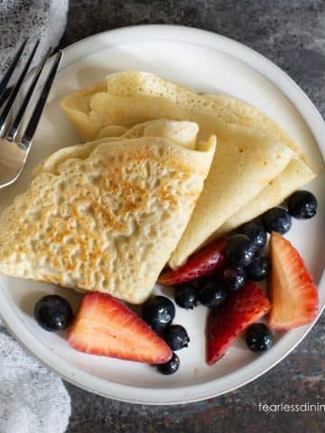 Folded crepes on a plate with fresh berries.