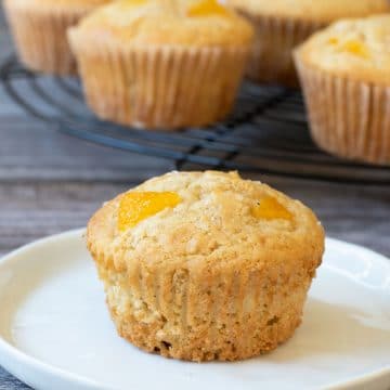 A peach muffin sitting on a small white plate.