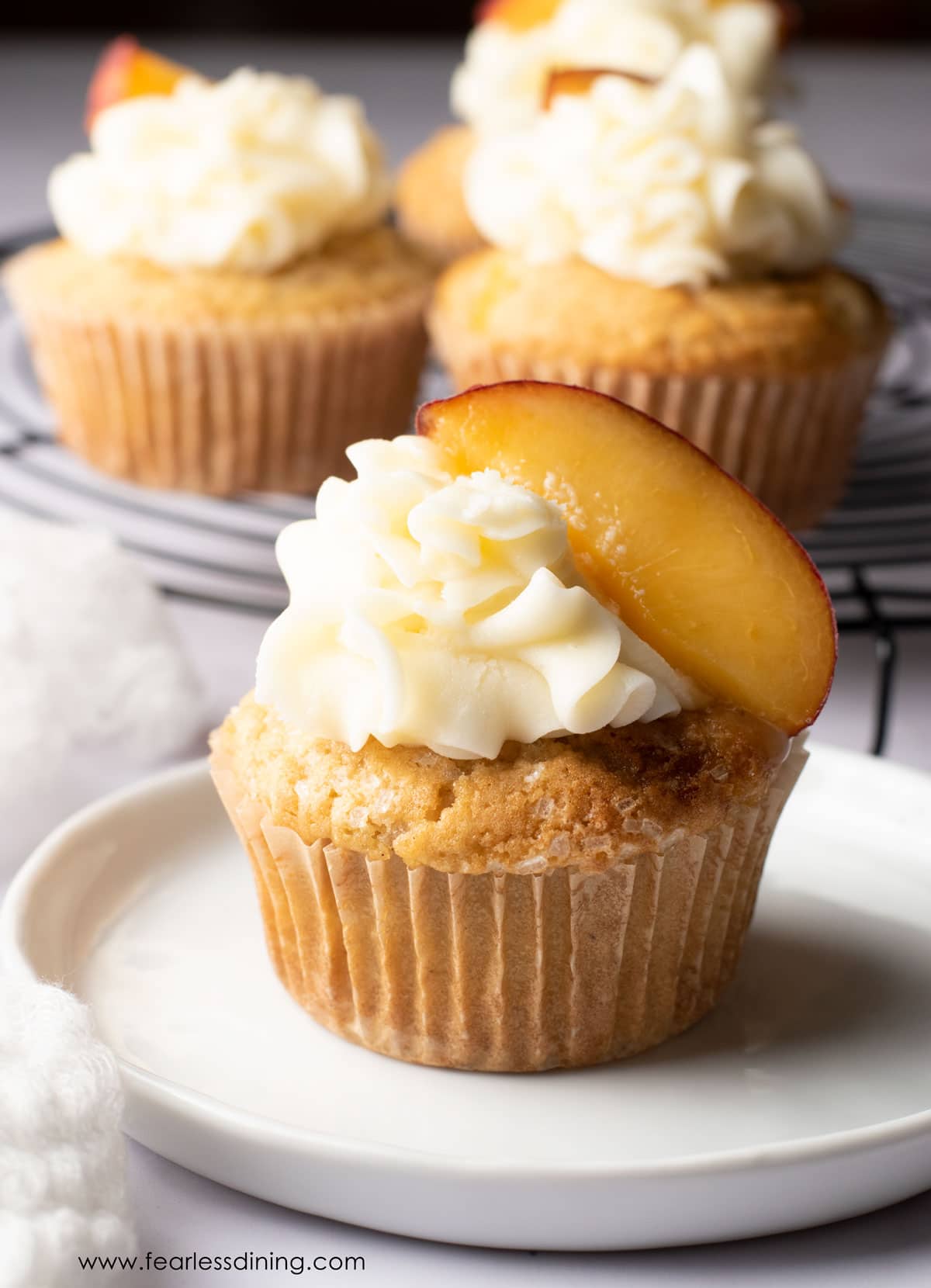 A peach cupcake on a small white plate.