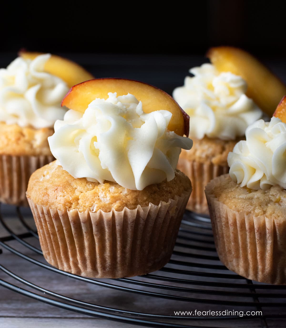 The frosted peach cupcakes on a wire rack.