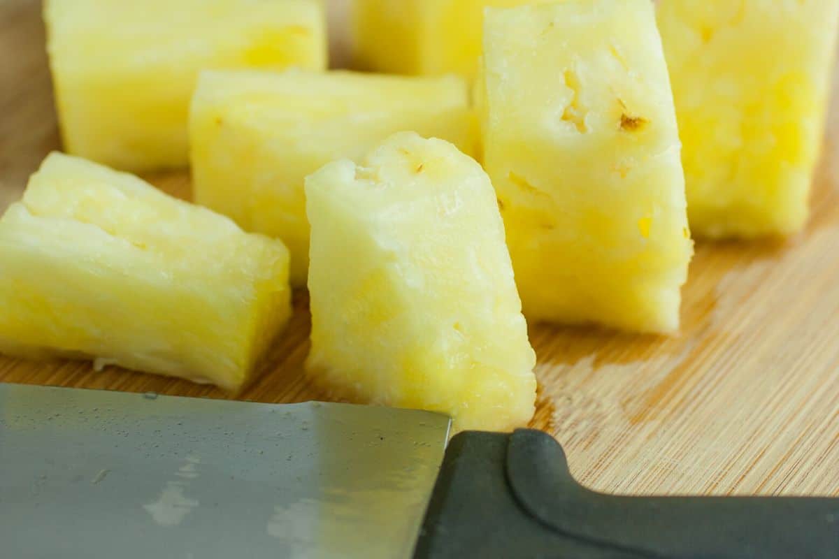 Cut pineapple chunks on a wooden cutting board.