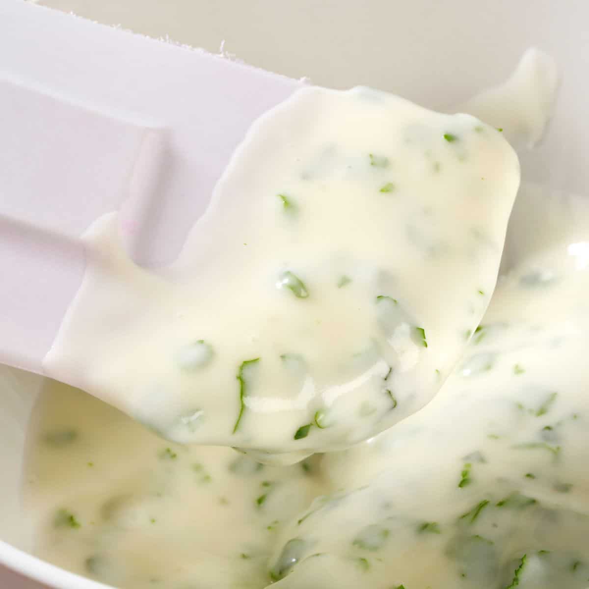 A close up of the ranch dressing on a white rubber spatula.