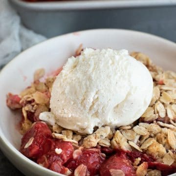 a bowl of gluten free strawberry rhubarb crisp with a scoop of vanilla ice cream.