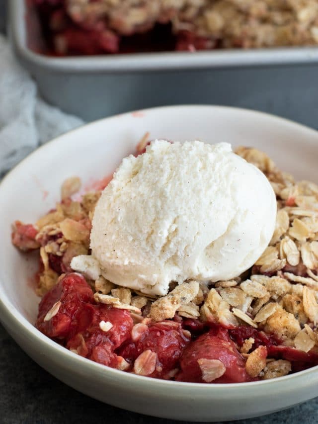 a bowl of gluten free strawberry rhubarb crisp with a scoop of vanilla ice cream.