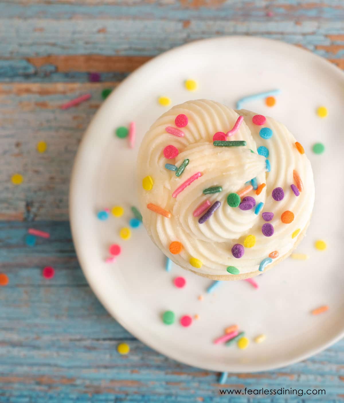 The top view of a cone cake decorated with vanilla frosting and rainbow sprinkles.