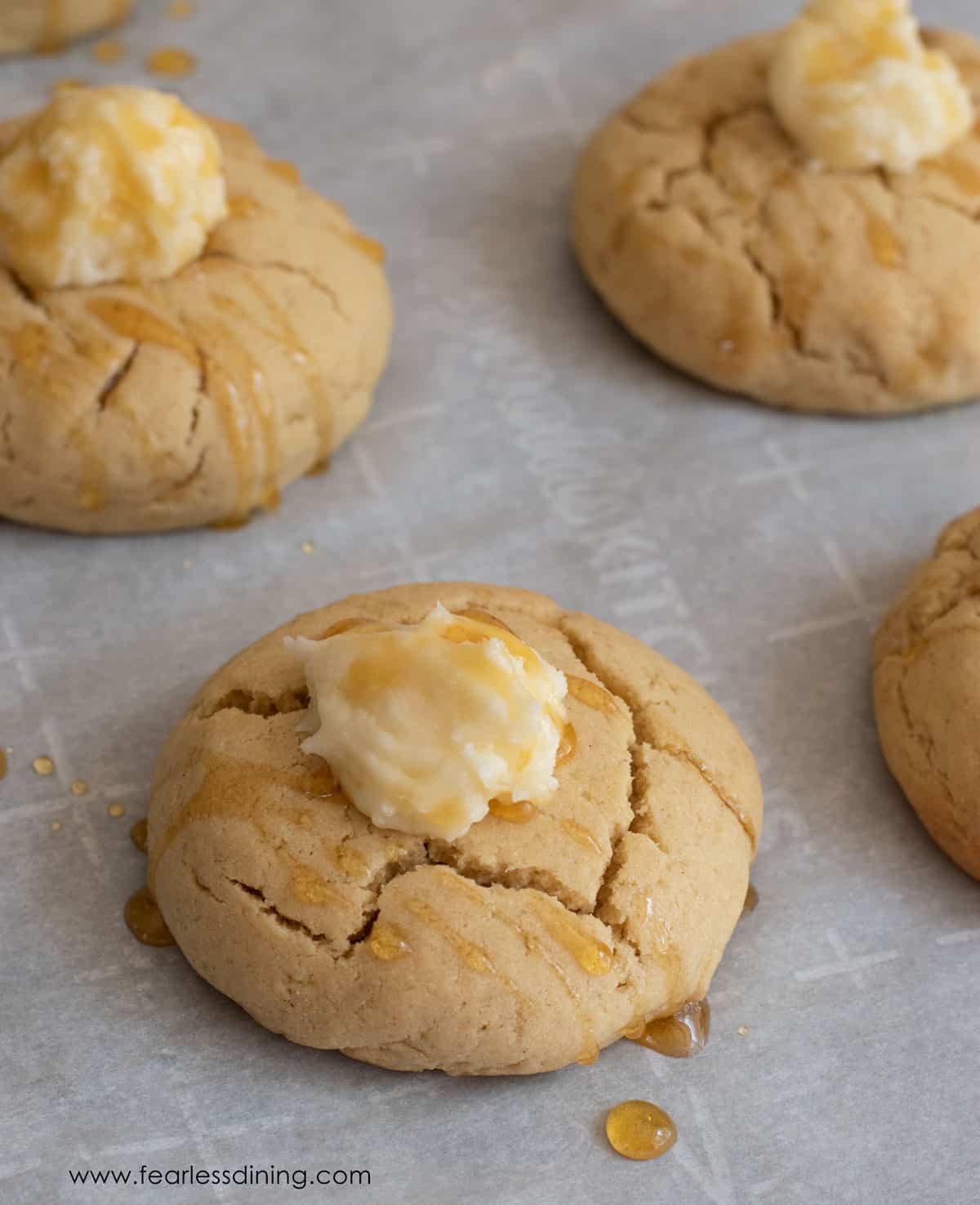 A tray of gluten free cornbread cookies topped with honey butter and honey.