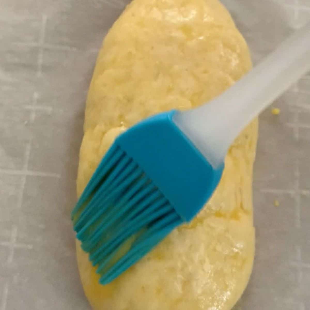 Brushing egg wash over a hot dog bun.