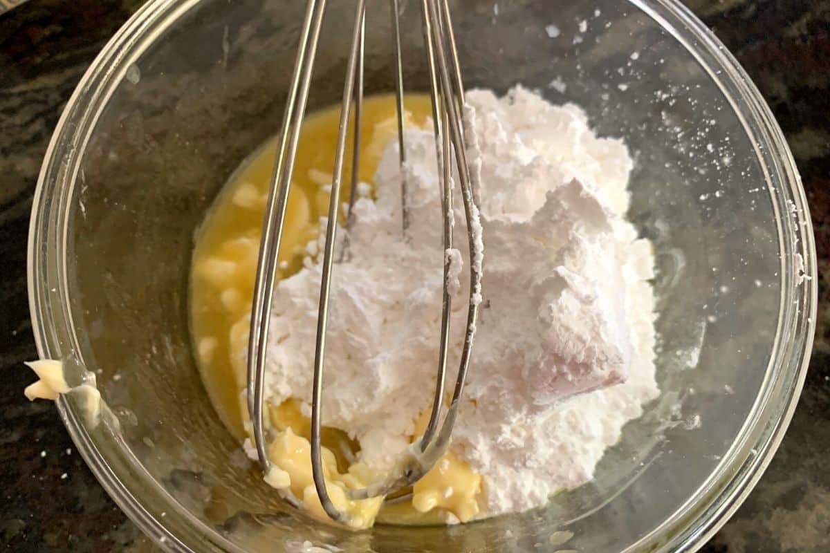 Honey butter ingredients in a glass bowl. A whisk is in the bowl.