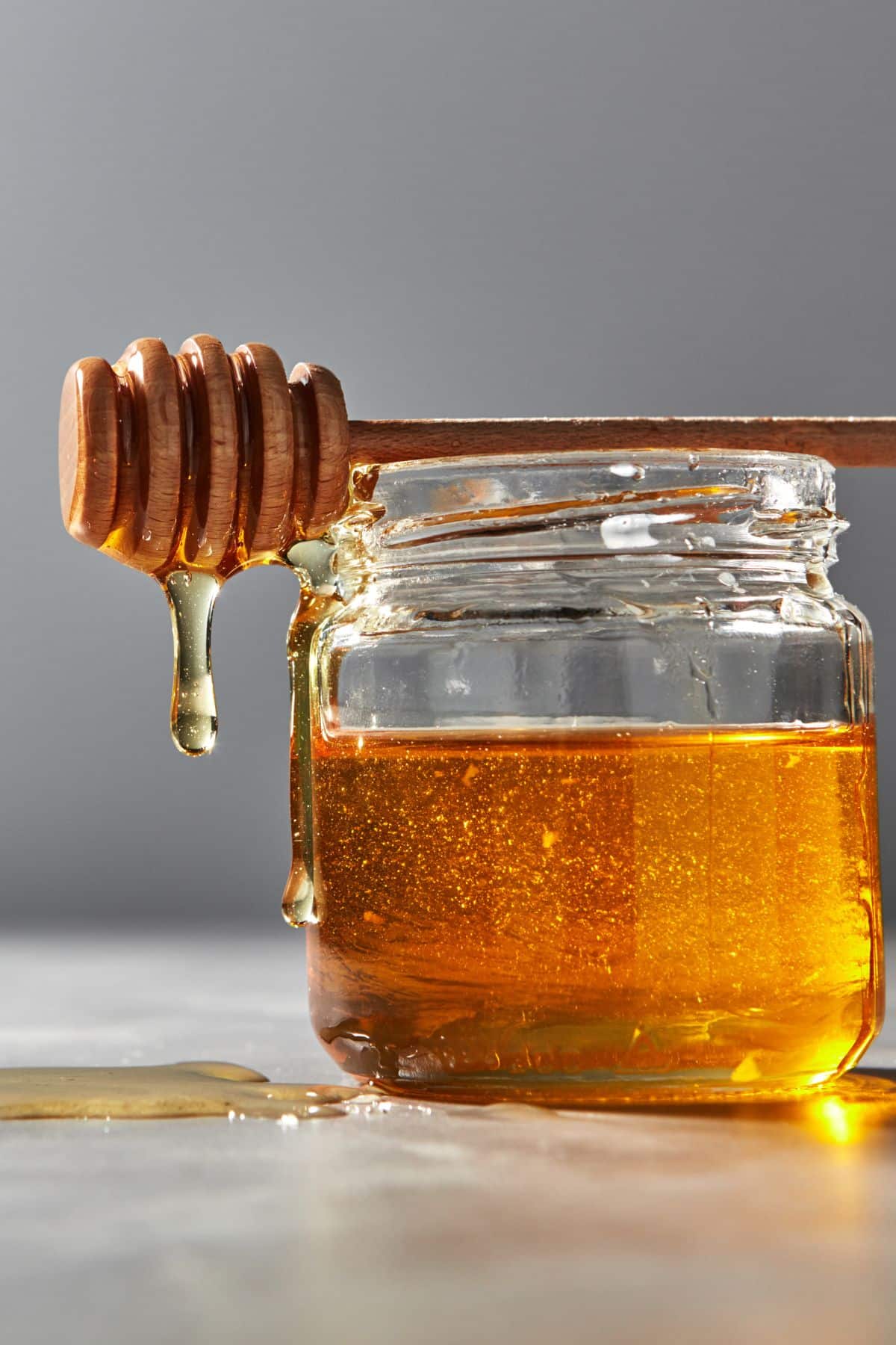 A small jar of honey with a wooden honey spoon.
