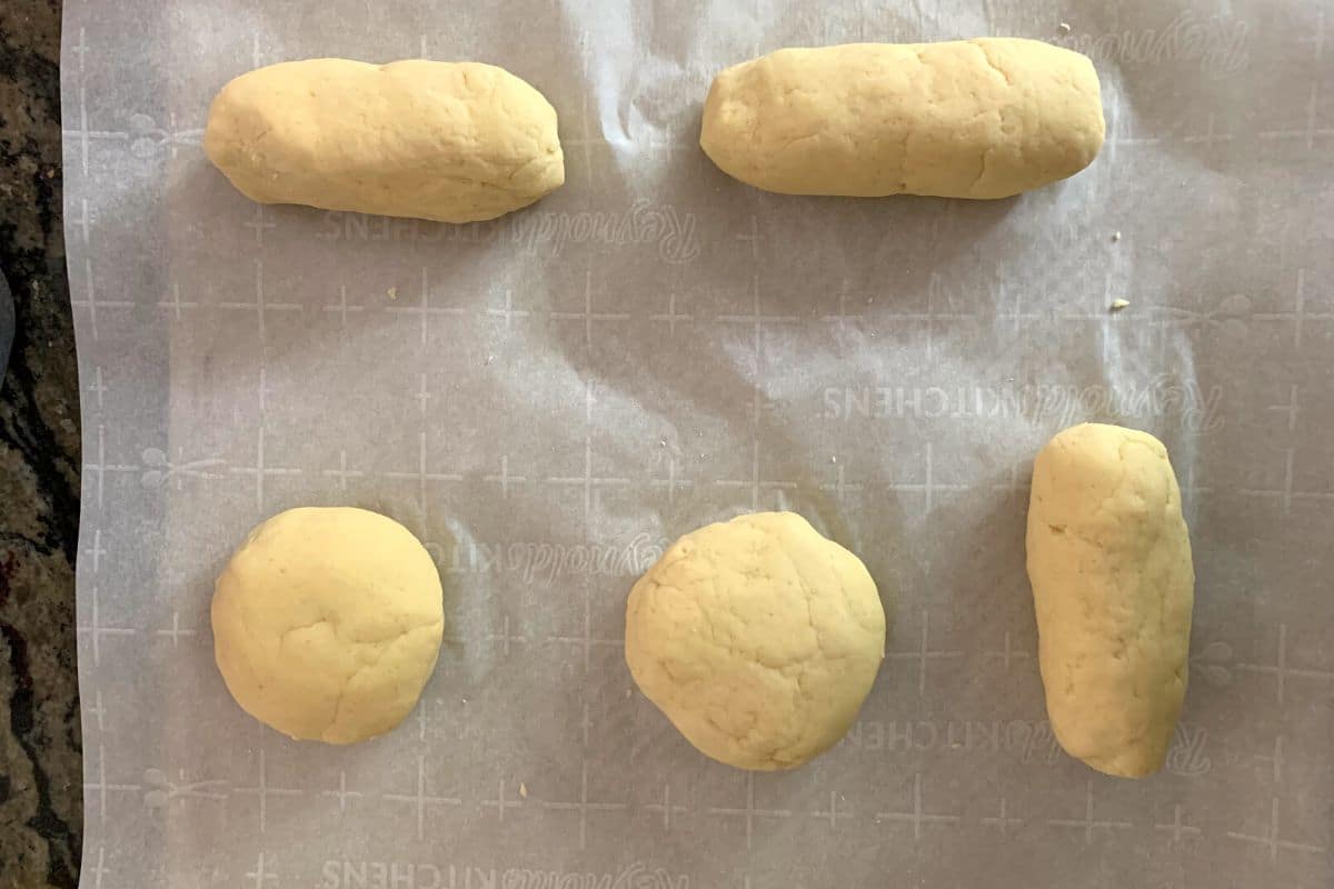 Hot dog and hamburger buns rising on a baking sheet.