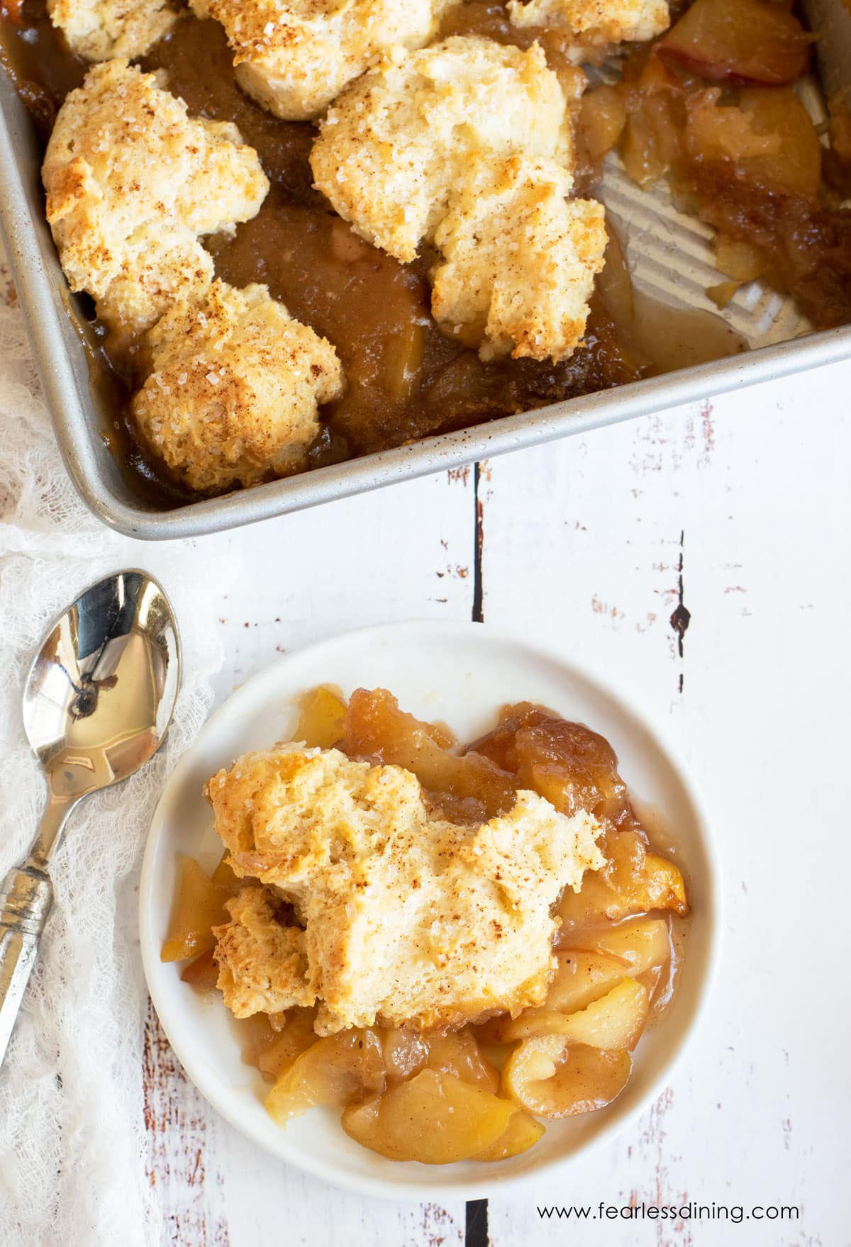 The top view of a bowl of gluten free apple cobbler next to the dish of cobbler.