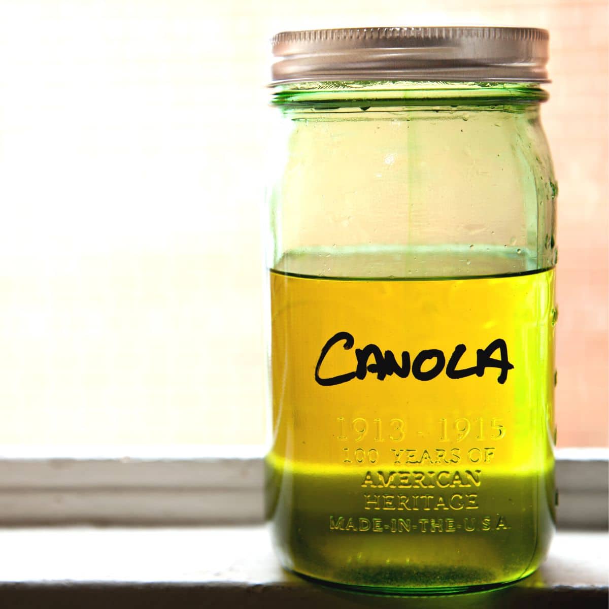 A jar of canola oil on a counter.