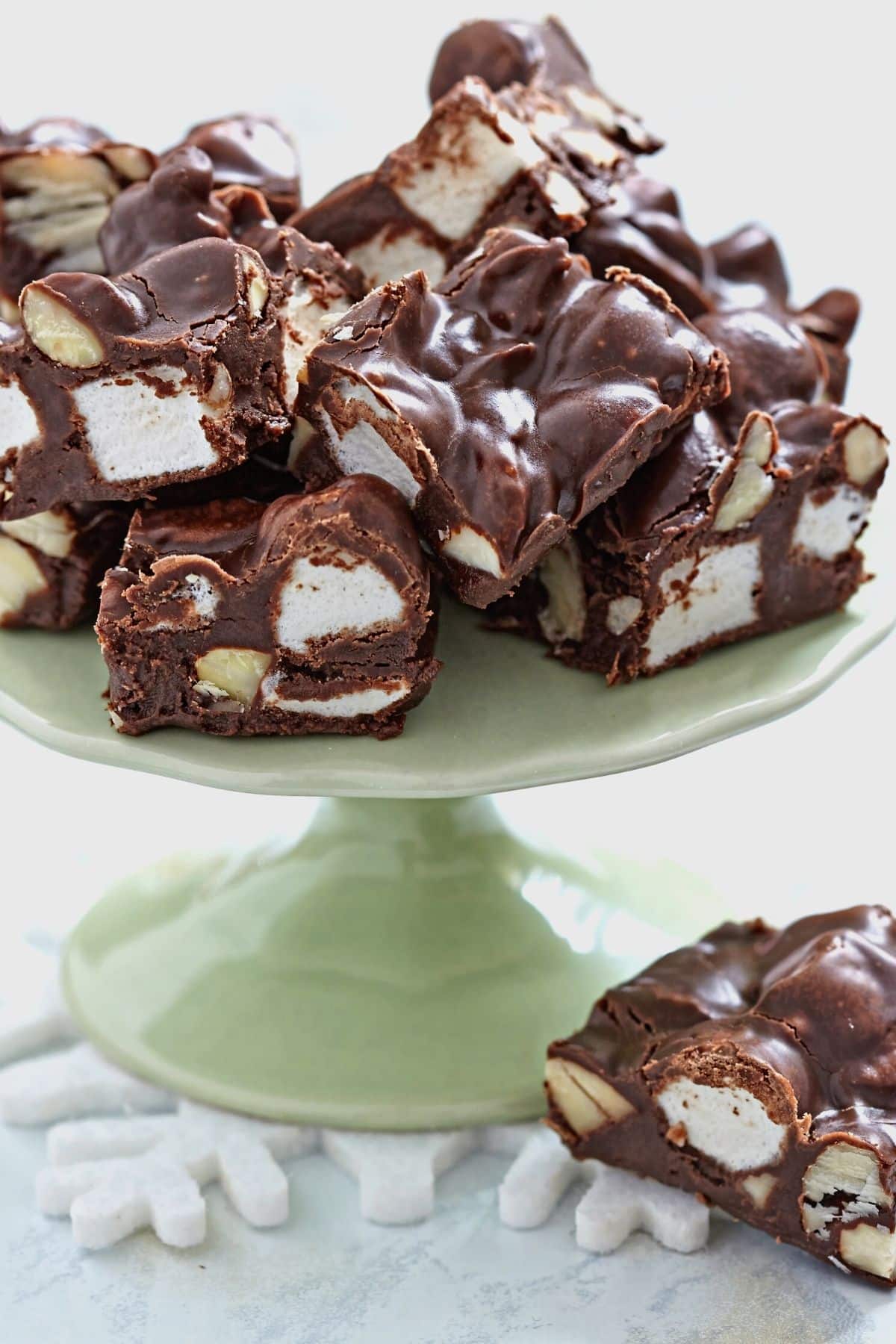 A pale green colored platter with fudge pieces on top.