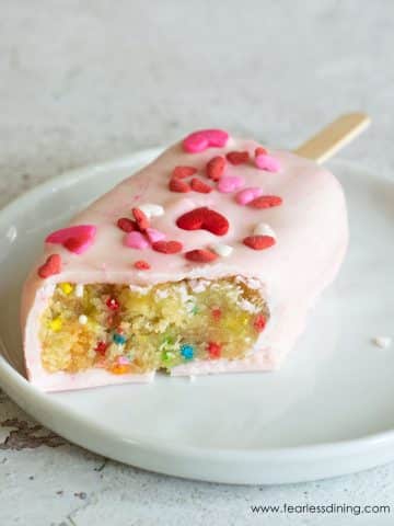 a funfetti cakesicle with a bite removed so you can see the funfetti cake inside.