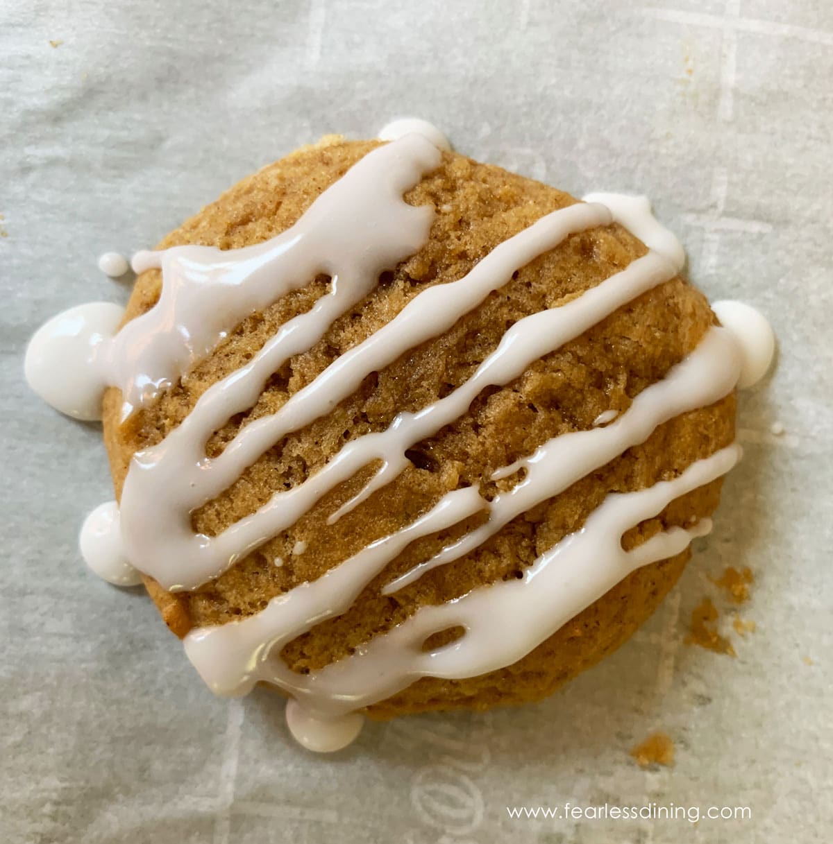An iced pumpkin cookie on a baking sheet.