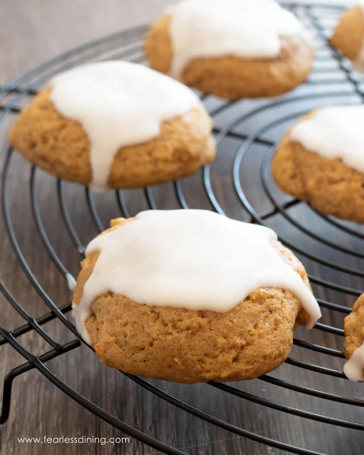 Iced pumpkin cookies on a black wire rack.