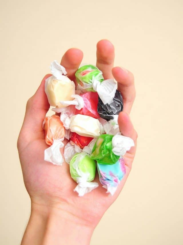 a hand holding wrapped salt water taffy pieces