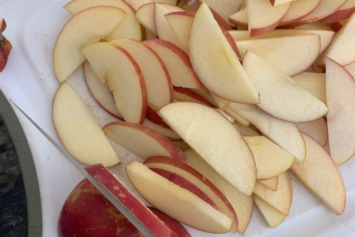 Sliced Pink Lady Apples on a white cutting board.