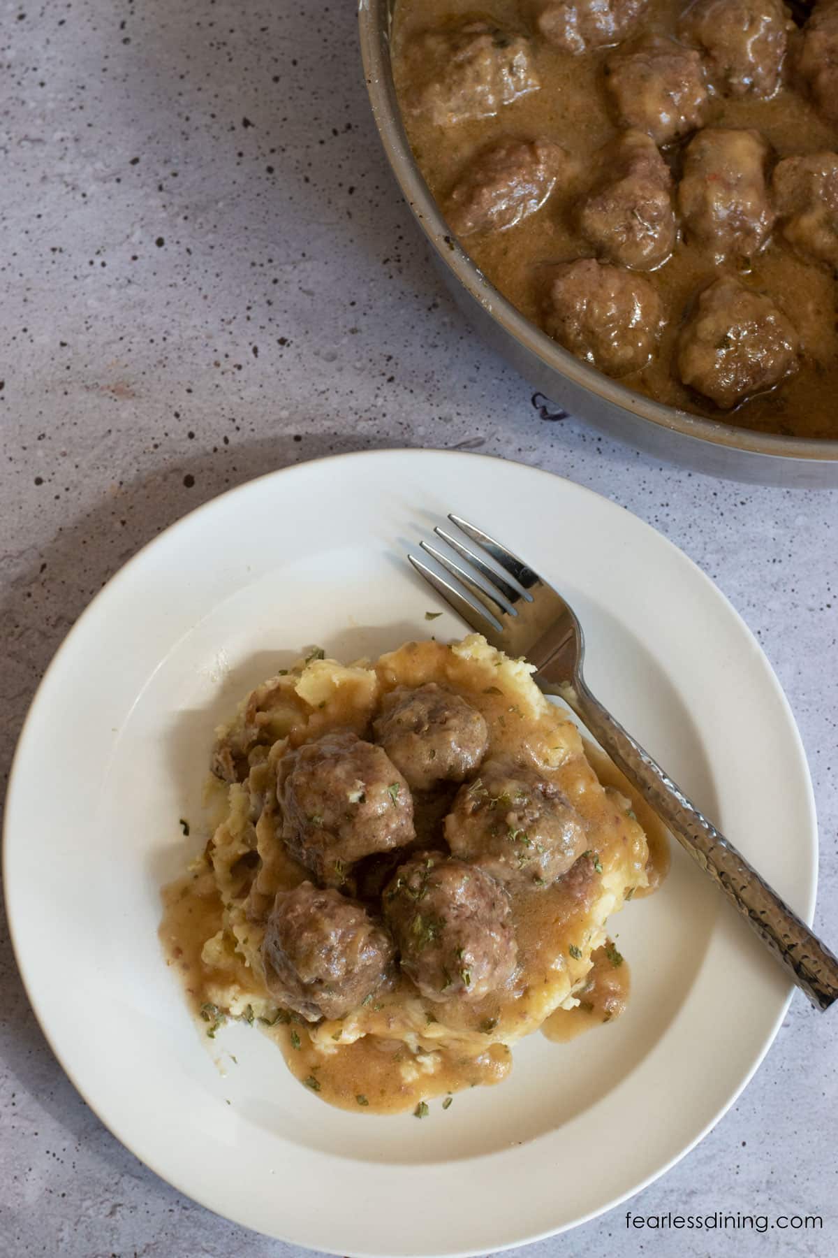 The top view of a plate full of mashed potatoes and Swedish meatballs.