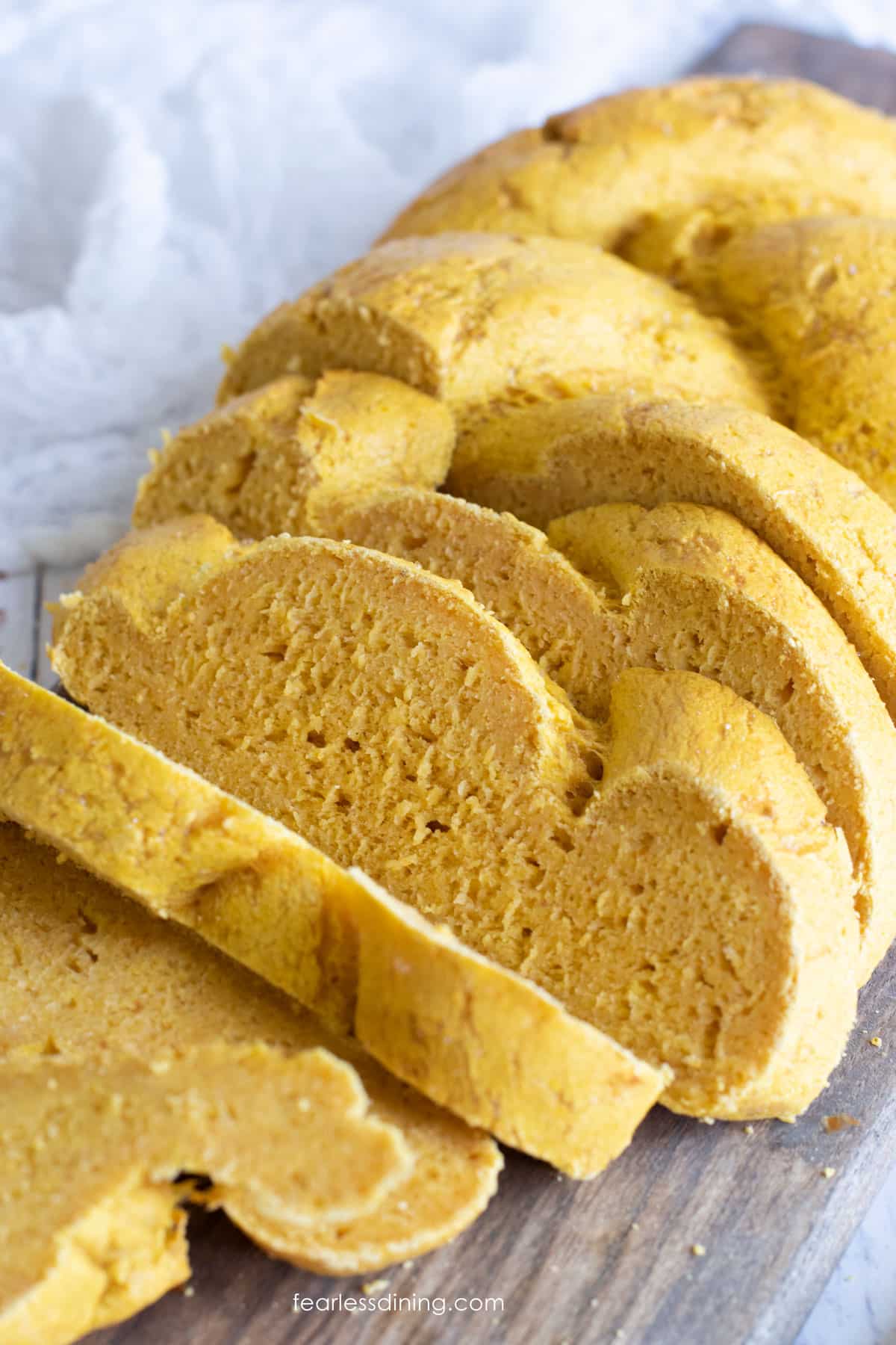 A sliced pumpkin challah on a cutting board.