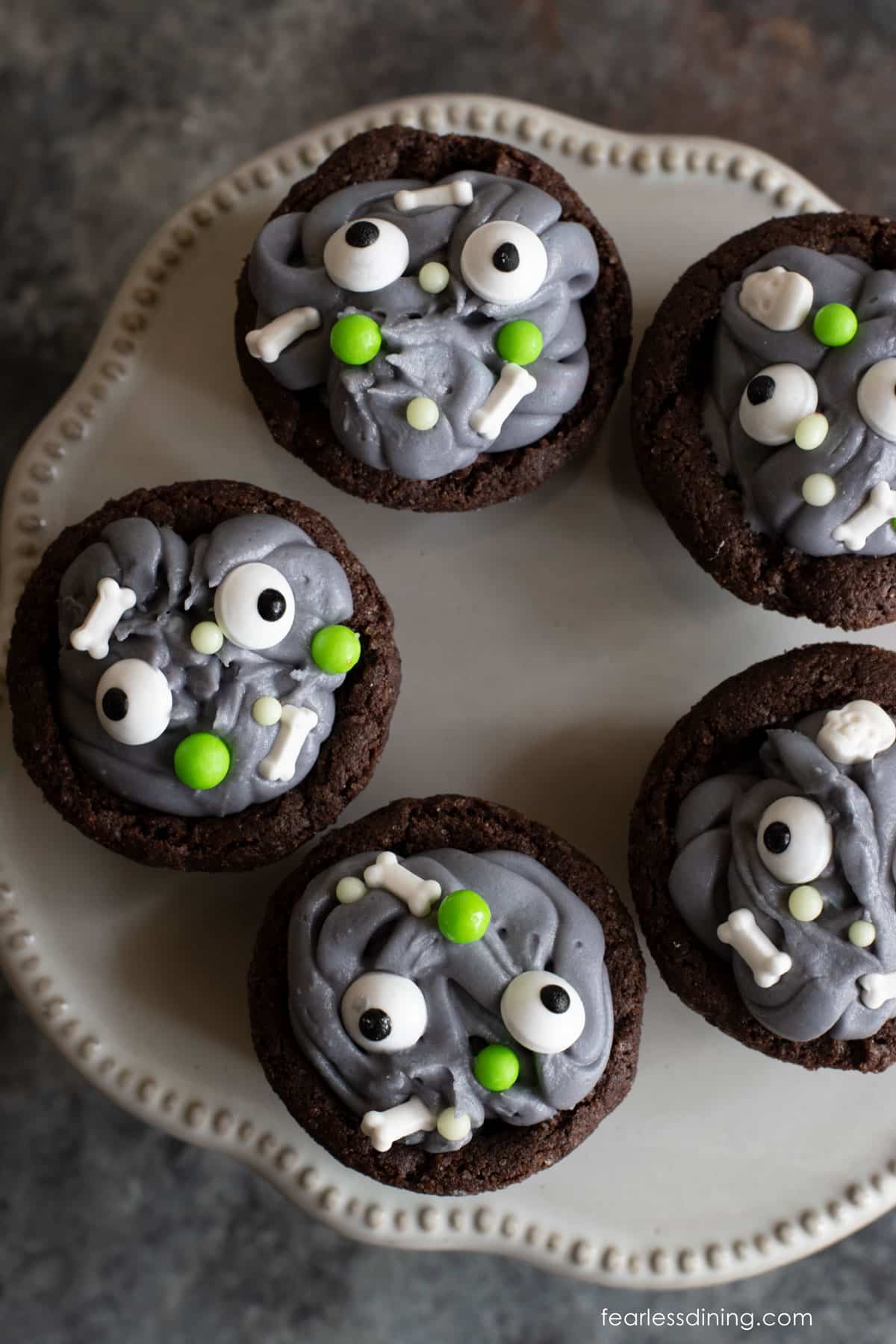 A small serving platter with chocolate cookie cups decorated like monsters.