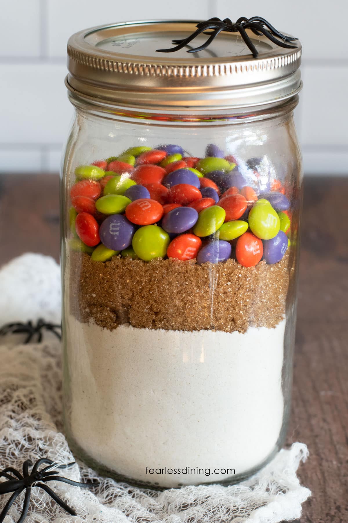 A mason jar filled with a gluten free Halloween cookie mix.