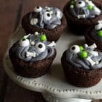 Monster cookie cups on a raised white cupcake platter.