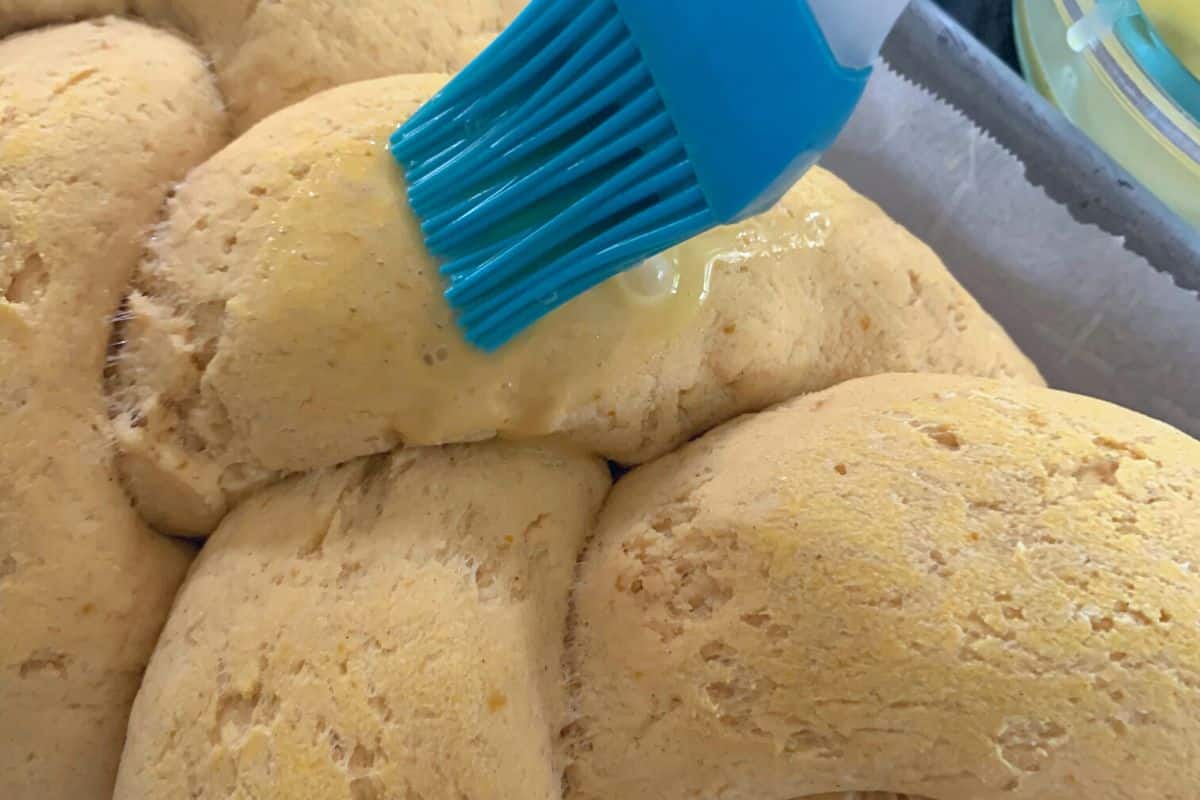 Brushing an egg wash over the challah prior to baking.