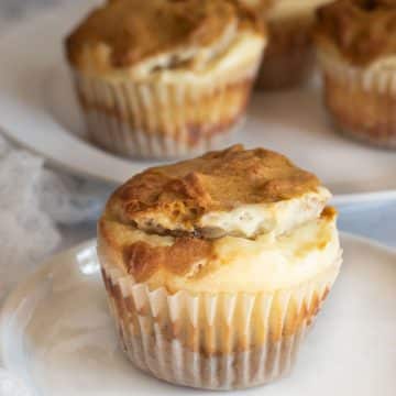 A pumpkin cream cheese muffin on a small white plate.