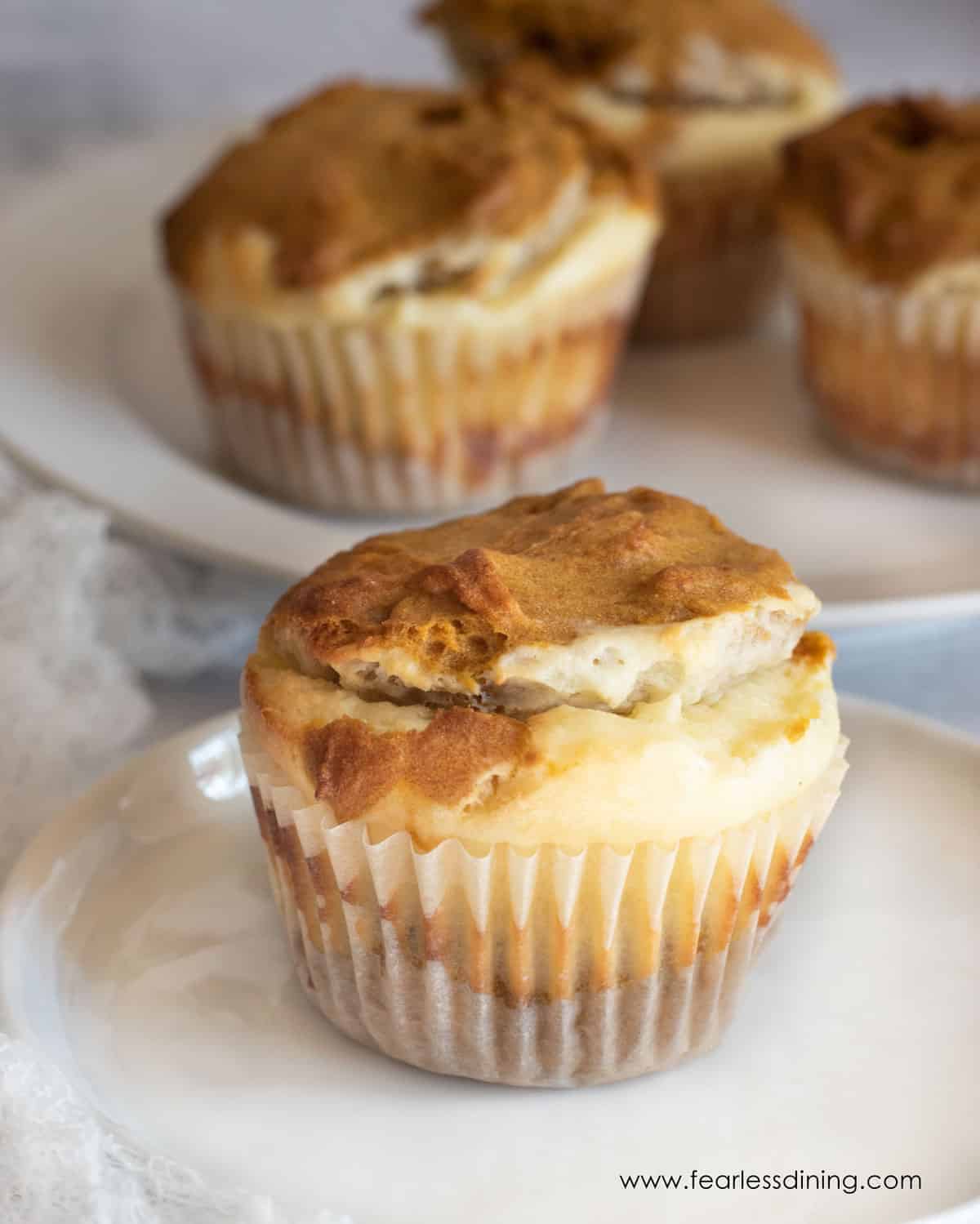 A pumpkin cream cheese muffin on a small white plate.