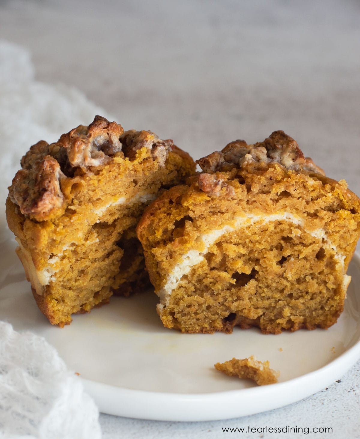 A pumpkin muffin cut in half on a plate.