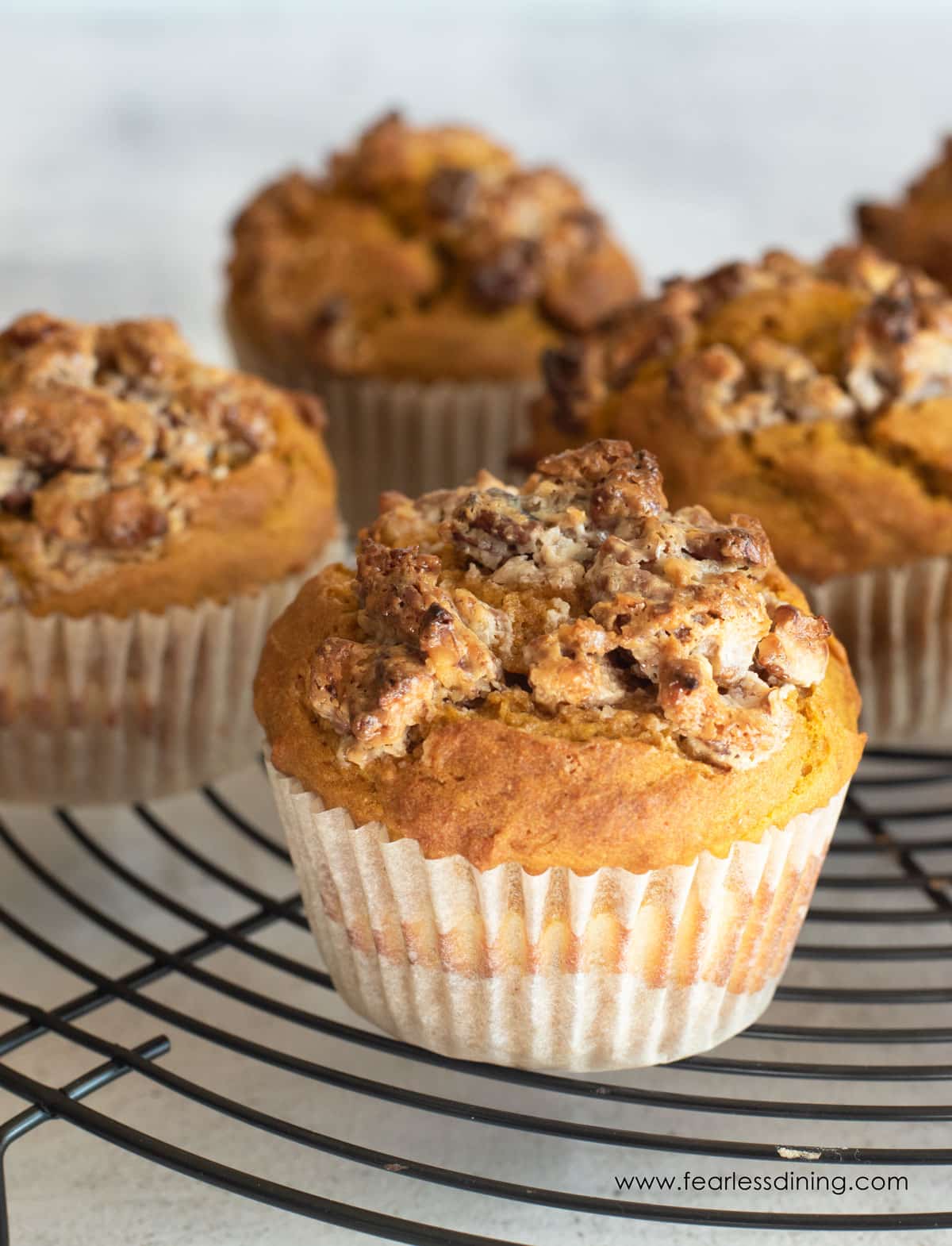 Pumpkin cream cheese muffins with streusel topping on a rack.
