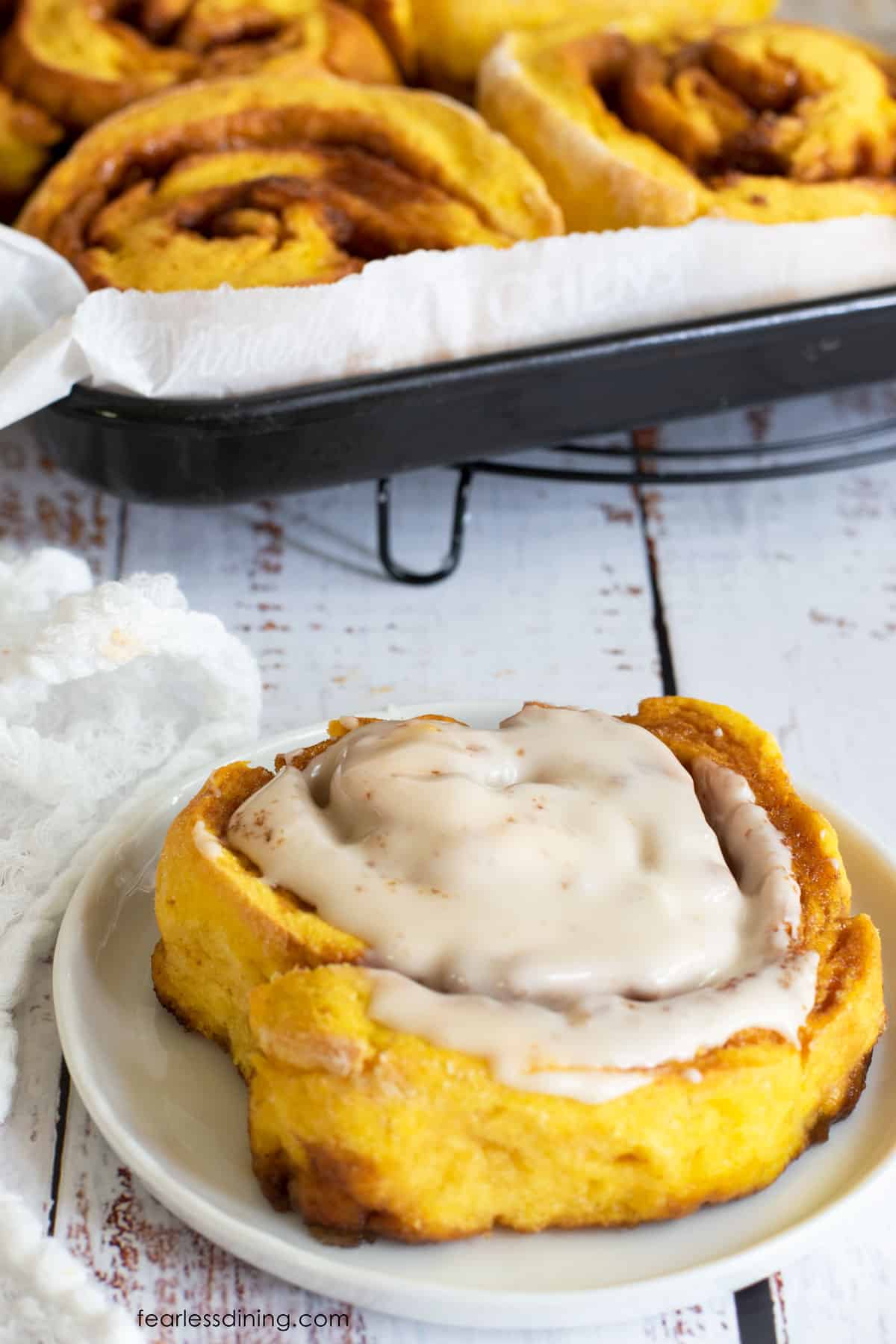 A picture of a pumpkin spice cinnamon roll on a plate.