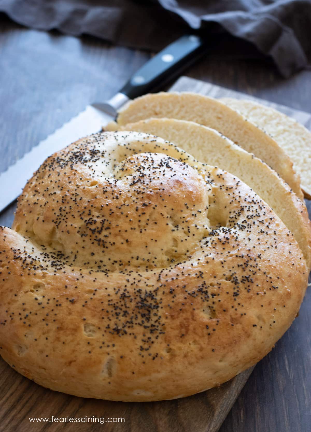 A round challah on a wooden cutting board.