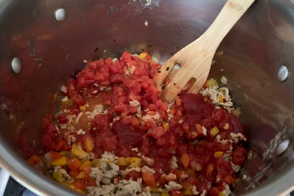Diced tomatoes added to the soup pot.