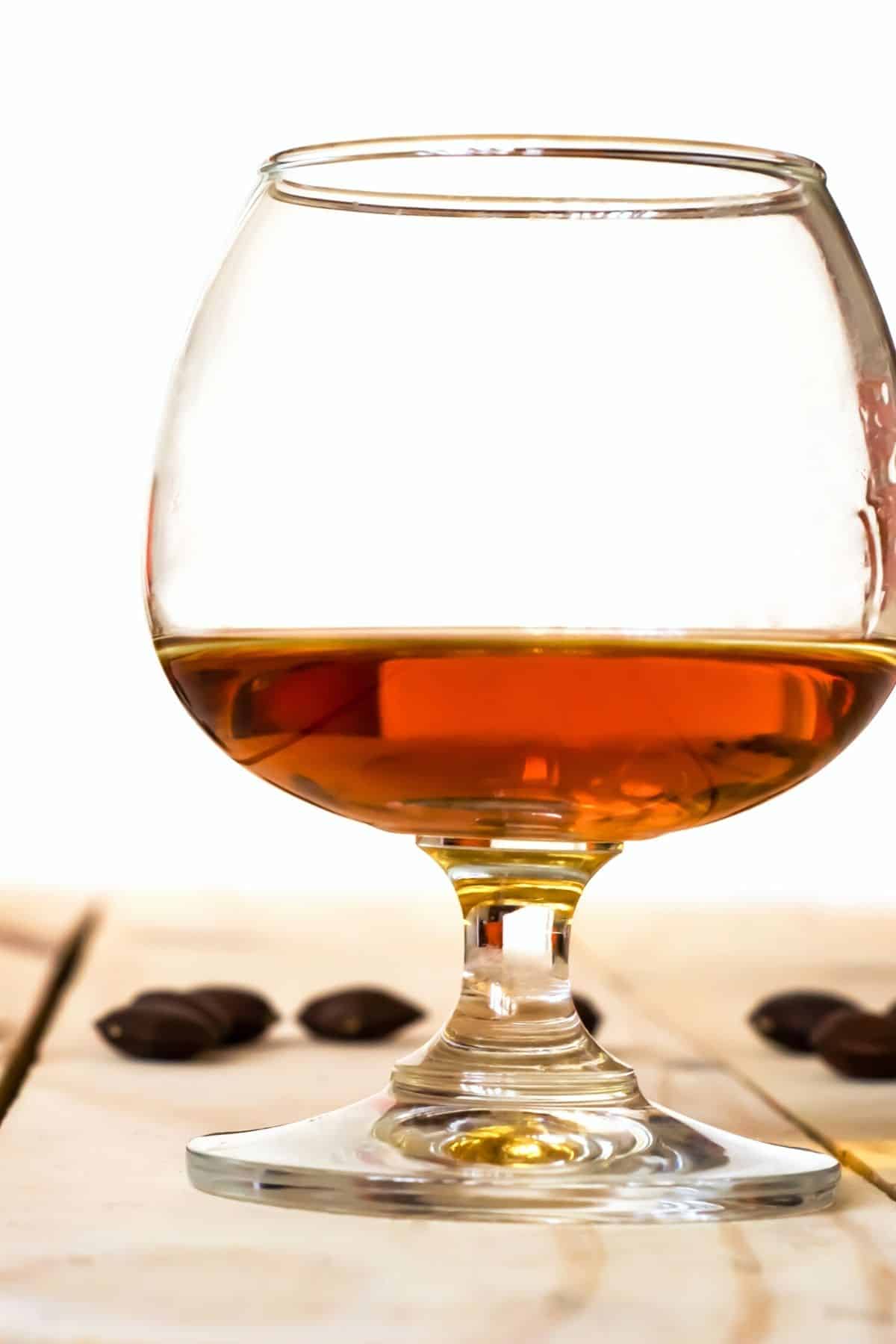 A glass snifter of brandy on a wooden table.