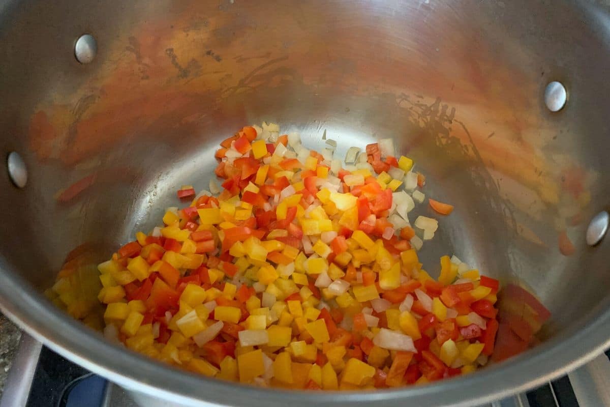 The diced onions and peppers cooking in a soup pot.