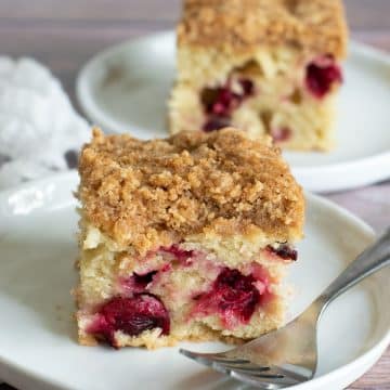 Two slices of cranberry coffee cake on white plates.