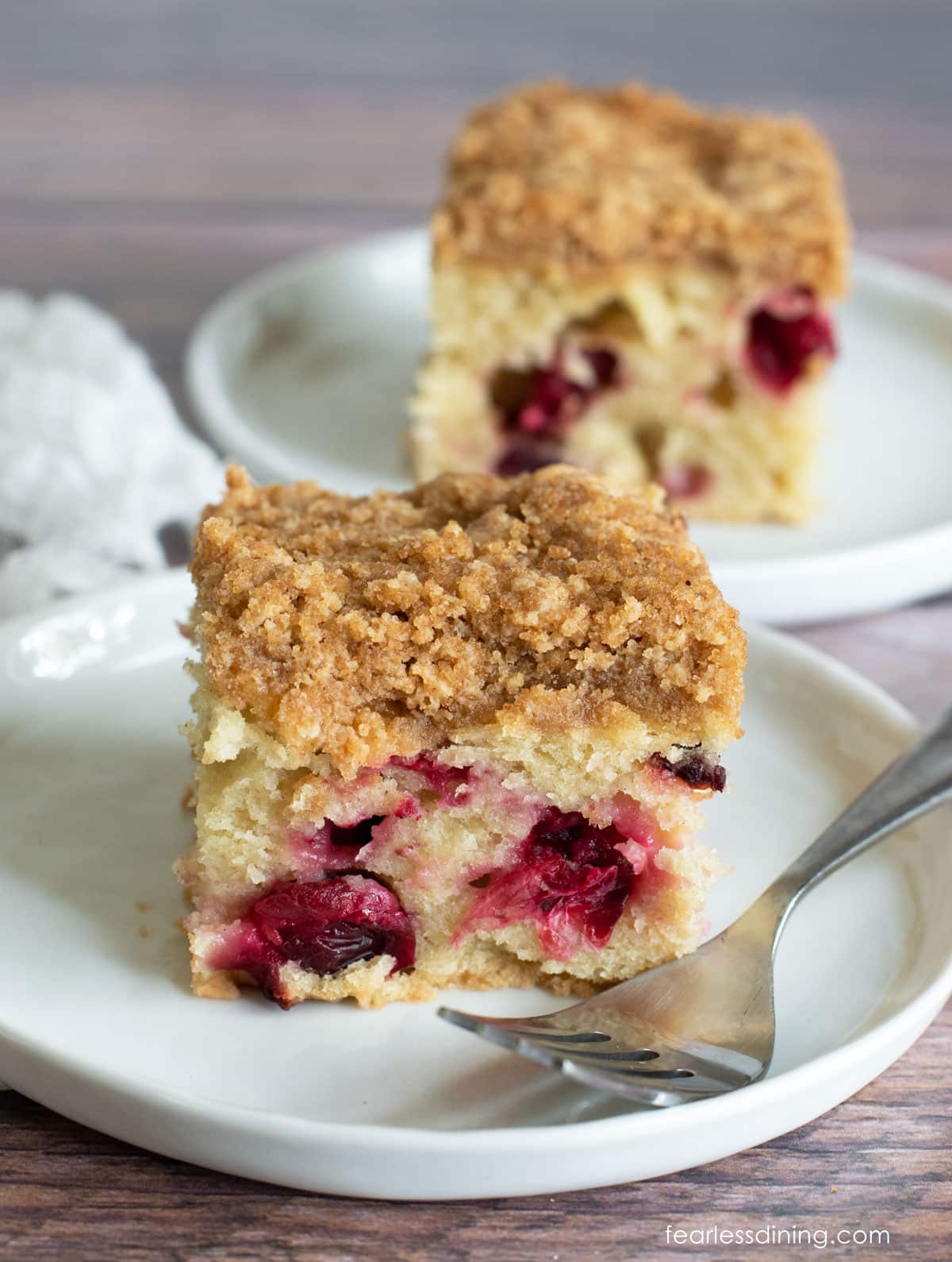 Two slices of cranberry coffee cake on white plates.