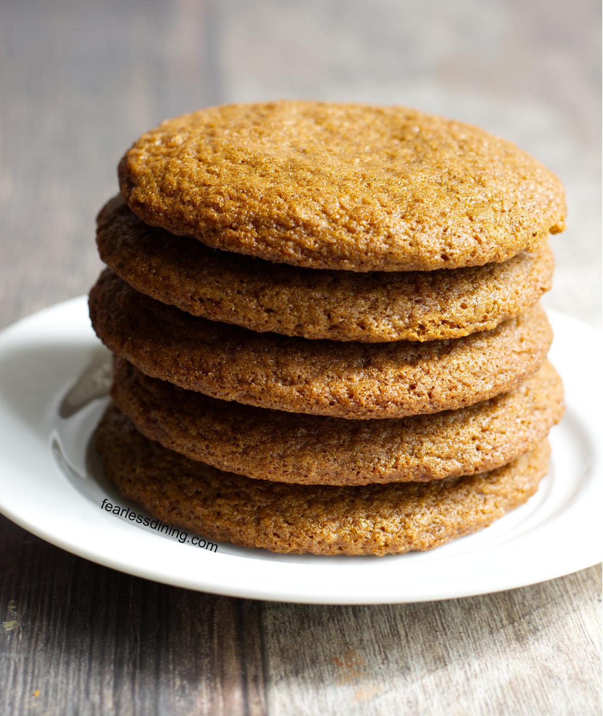 A stack of five gluten free molasses cookies on a plate.