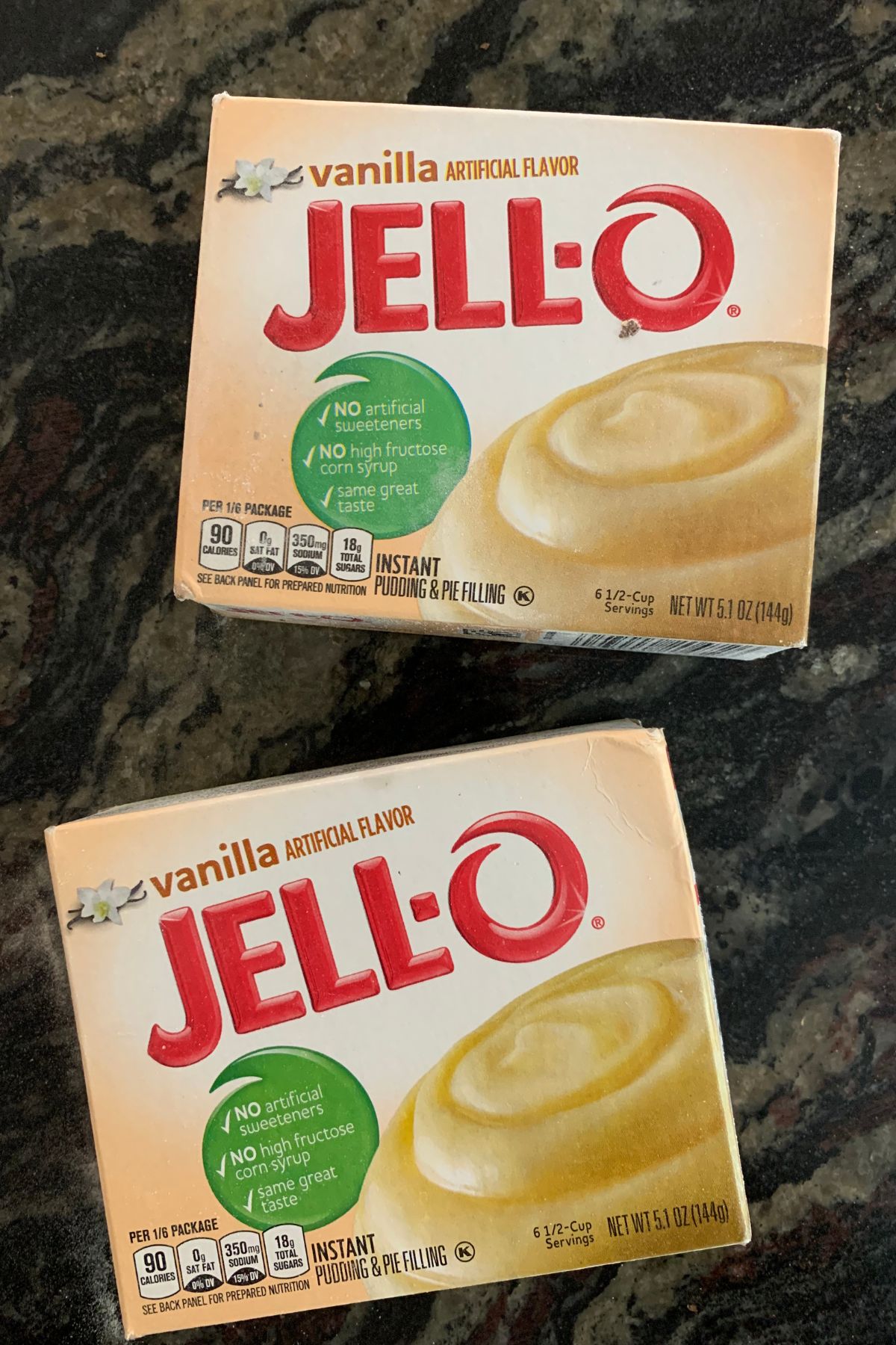 Two boxes of vanilla Jello pudding on a granite countertop.