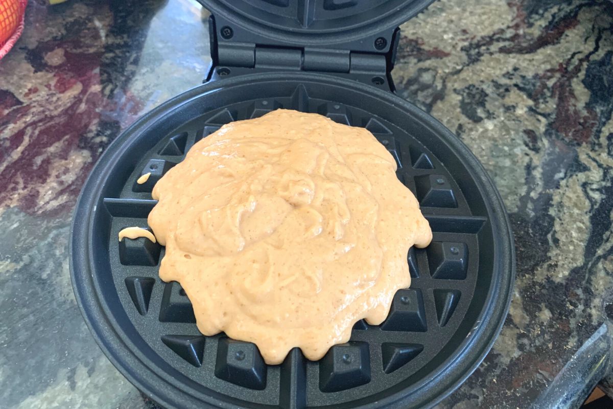 A photo of the waffle batter in a waffle iron.