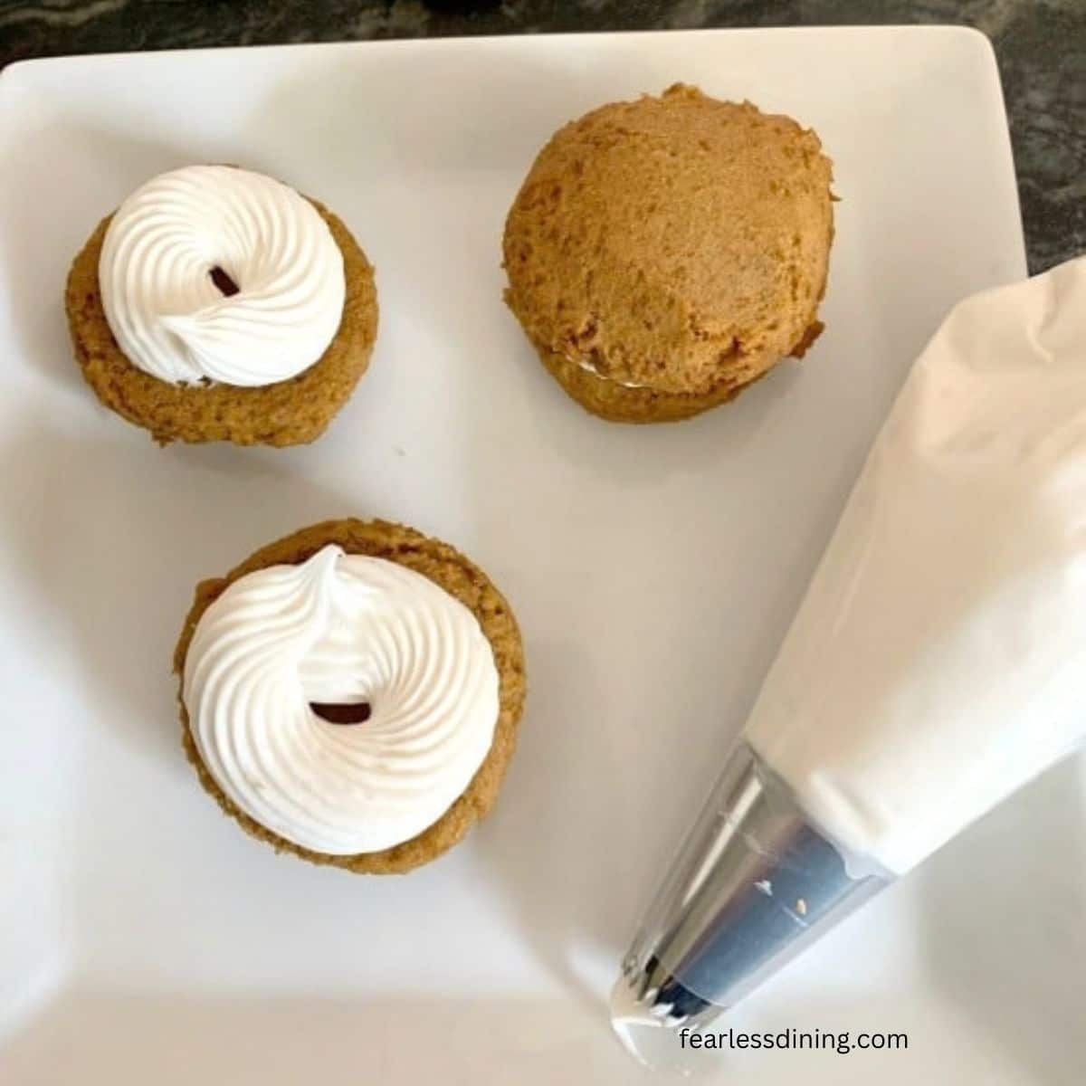 Piping the frosting onto the whoopie pie halves.
