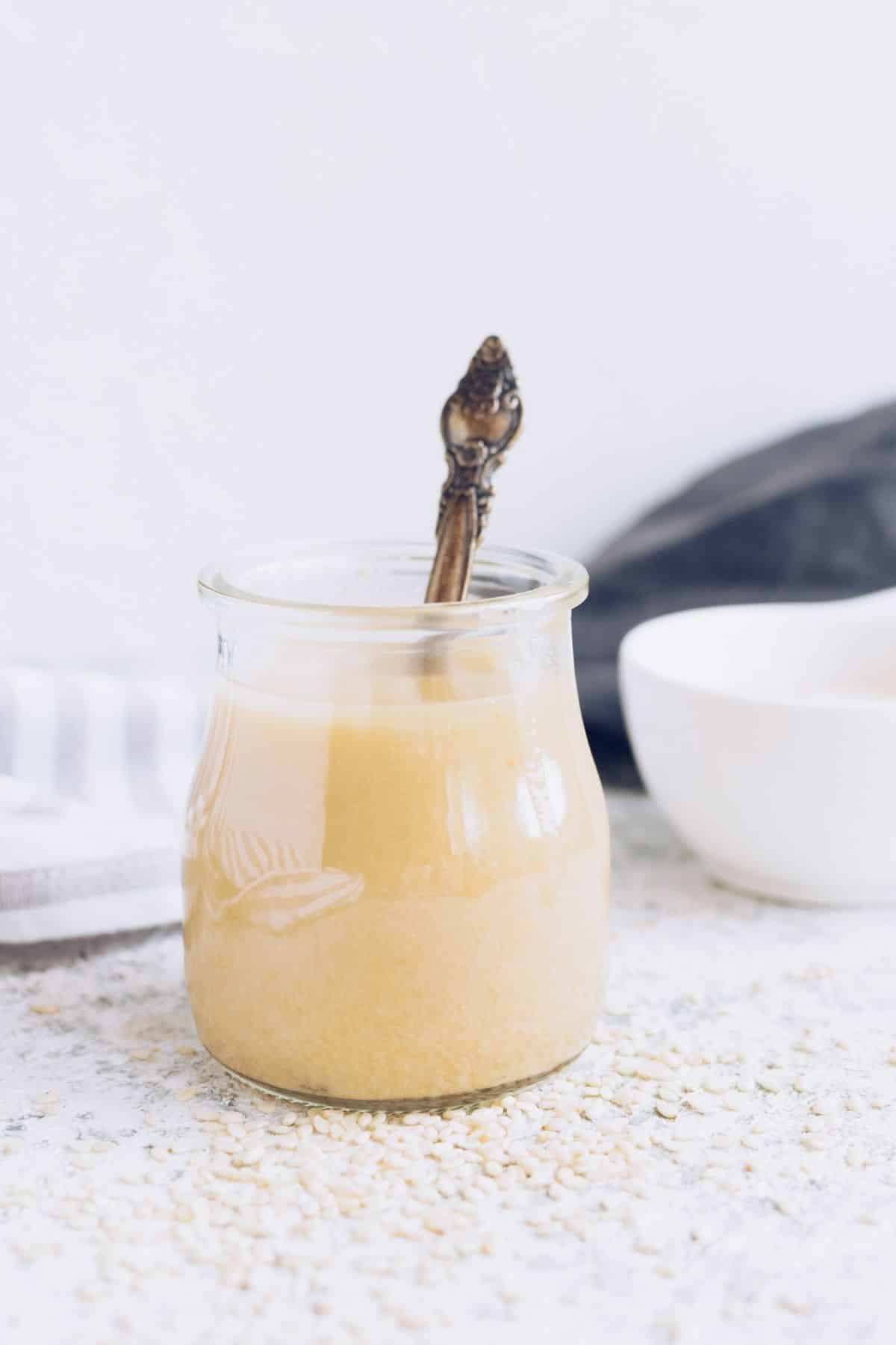a small jar of tahini with a spoon in it.