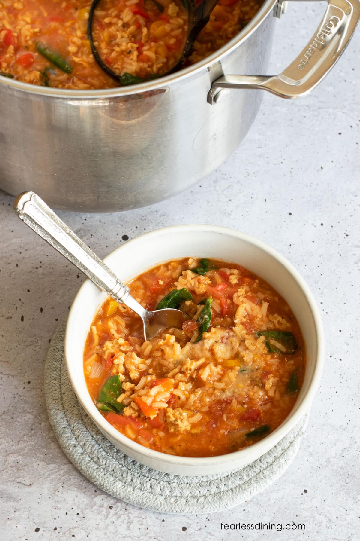 The top view of a bowl of soup next to the soup pot.