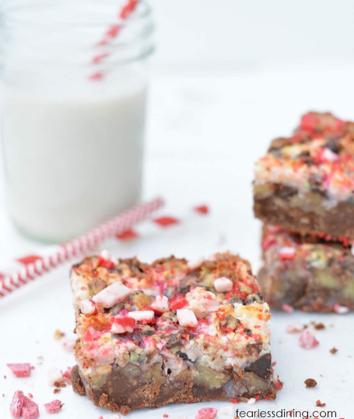 A peppermint 7 layer bar on the table next to a glass of milk.