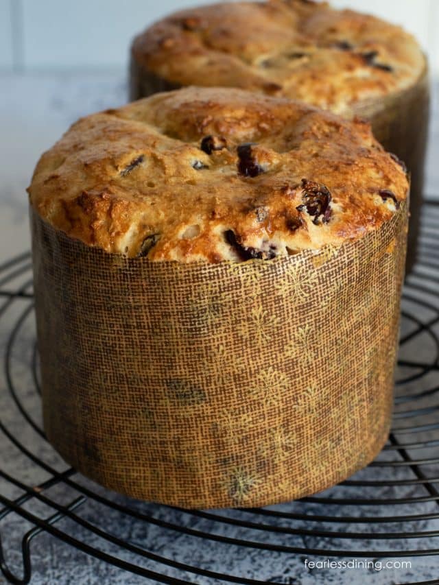 Two baked loaves of gluten free panettone bread on a rack.