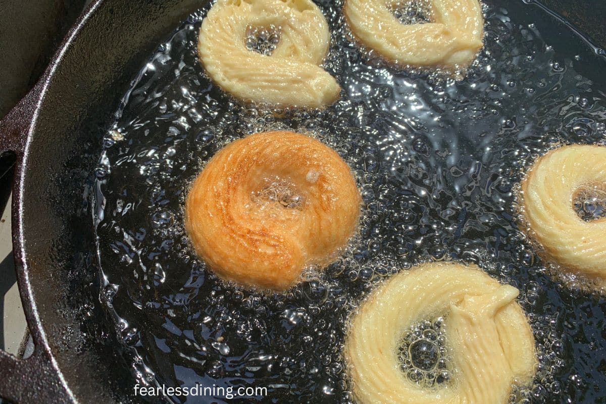 Gluten-free donuts frying in hot oil.